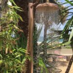 The Naeco Copper Outdoor Shower pole in leafy setting